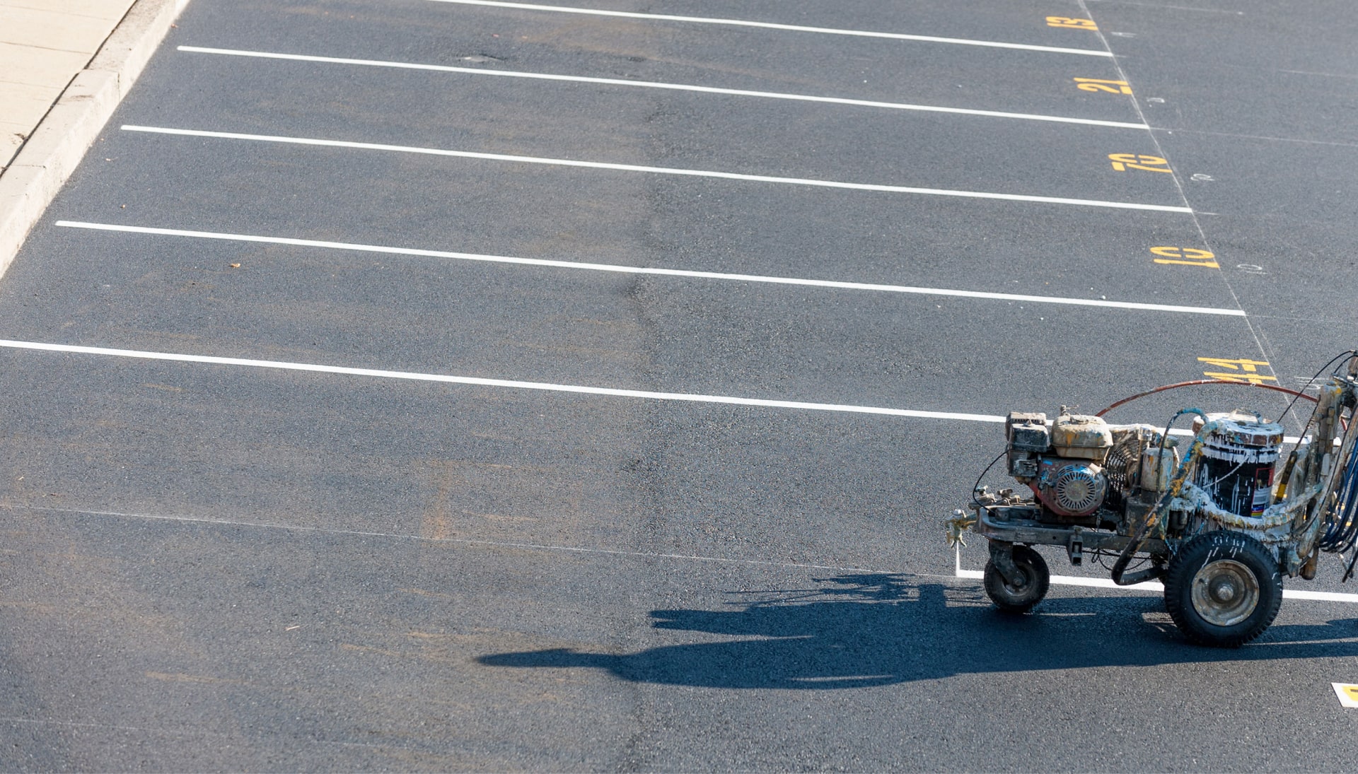 A professional parking lot striping machine creates lines and space numbers in a parking lot in Saint Paul, MN.