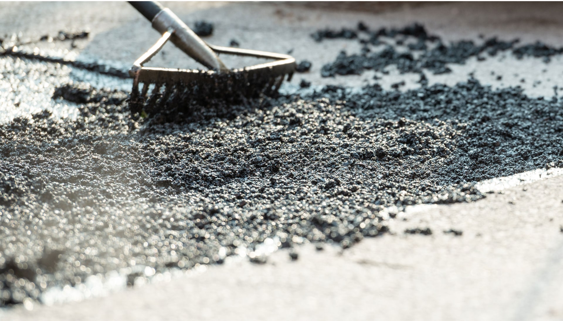 A rake is used to perform asphalt repair on a road in Saint Paul, MN.