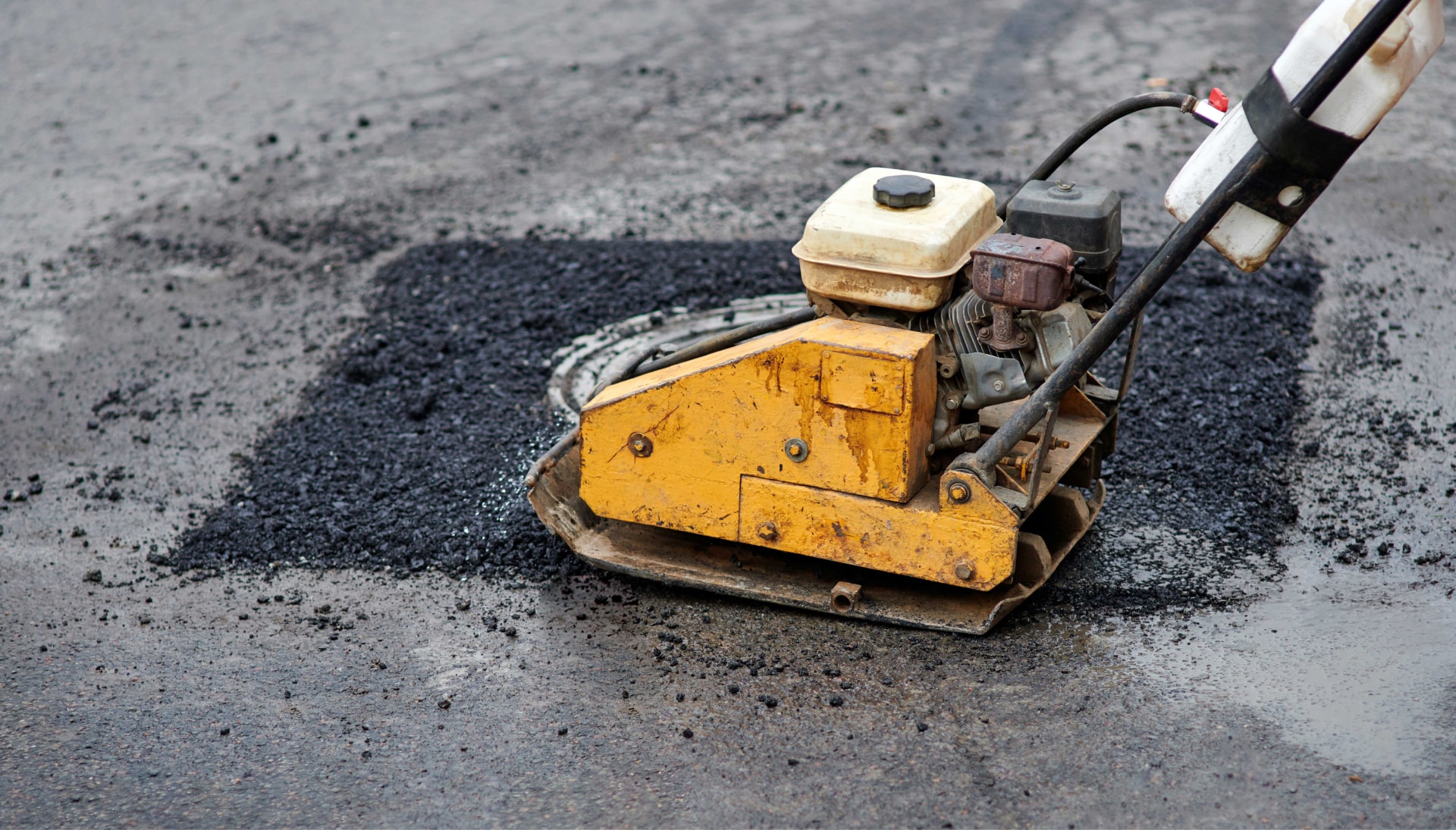 A small asphalt repair machine is used to create a small asphalt patch on a road in Saint Paul, MN.